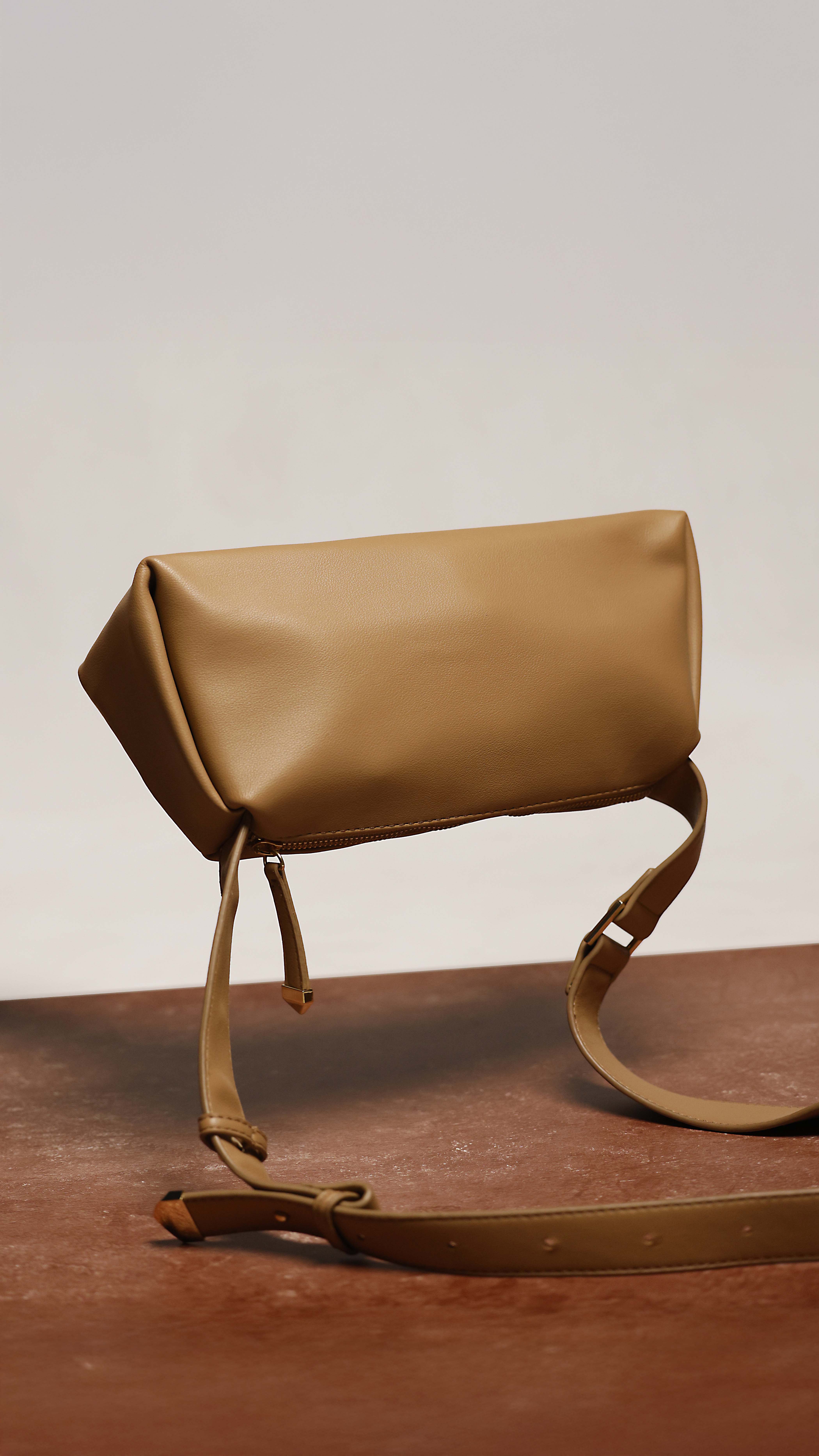 Brown leather handbag on wooden surface